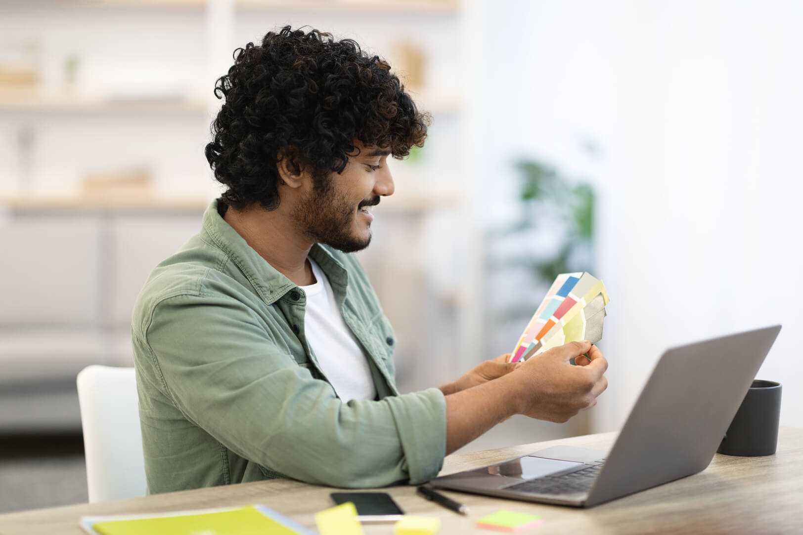 cheerful-darkskinned-guy-sitting-workdesk-front-laptop (1) (1)